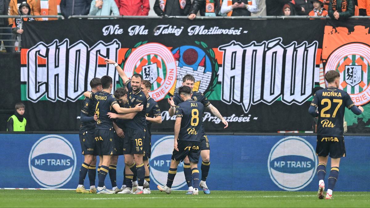 Piłkarze Lecha Poznań świętują zdobycie bramki na tle transparentu kibiców.