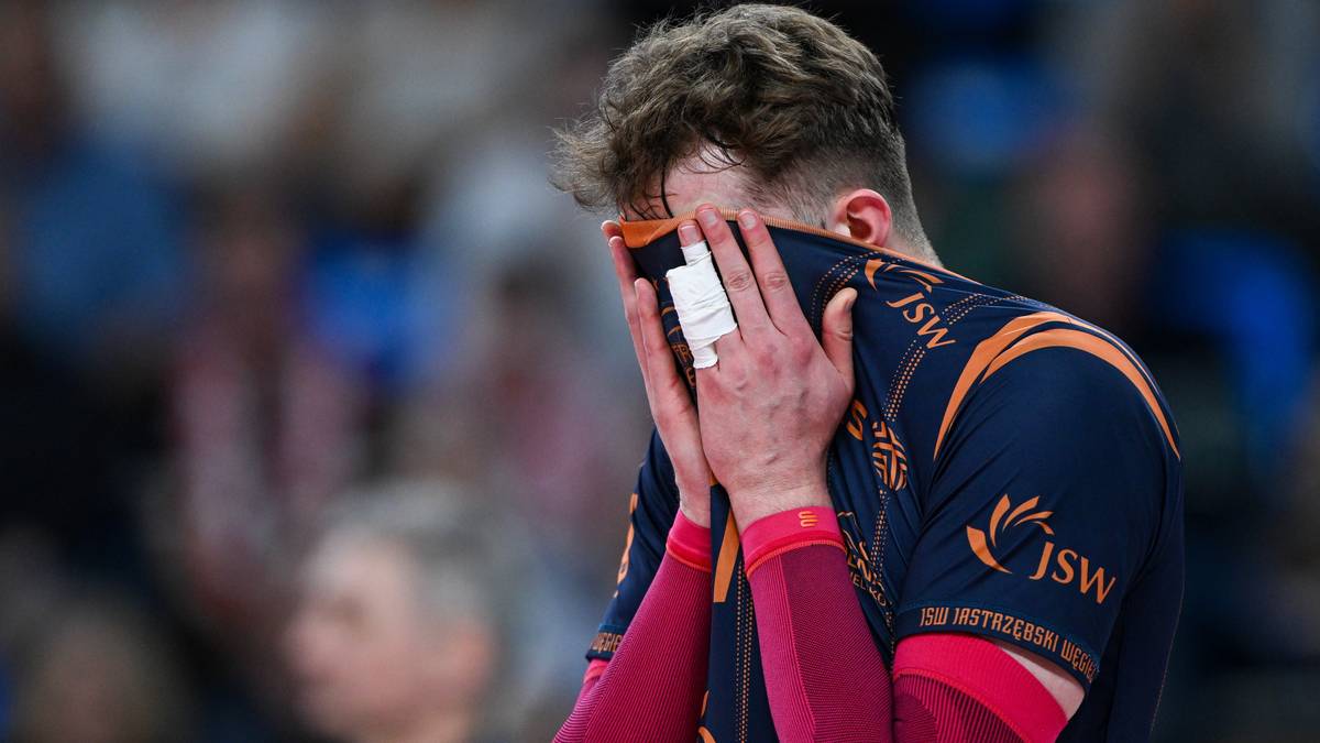 Siatkarz JSW Jastrzębski Węgiel zakrywa twarz dłońmi, na kt&oacute;rych widać ślady potu.