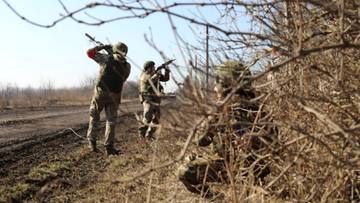Trzech żołnierzy w kamuflażu z karabinami, ukryci za krzakami, obserwuje otoczenie w słoneczny dzień.
