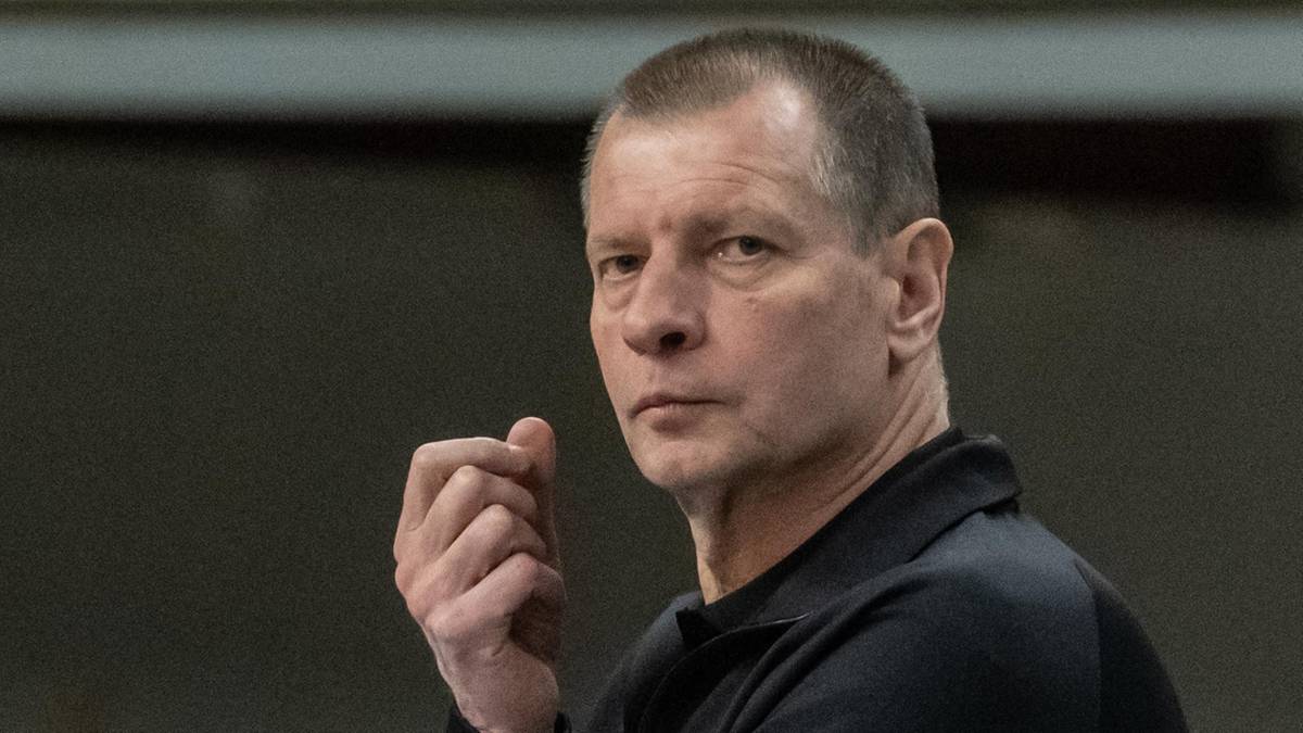 Portret mężczyzny w średnim wieku, ubranego w czarną koszulę. Ma kr&oacute;tkie włosy, a jego twarz wyraża skupienie i powagę.