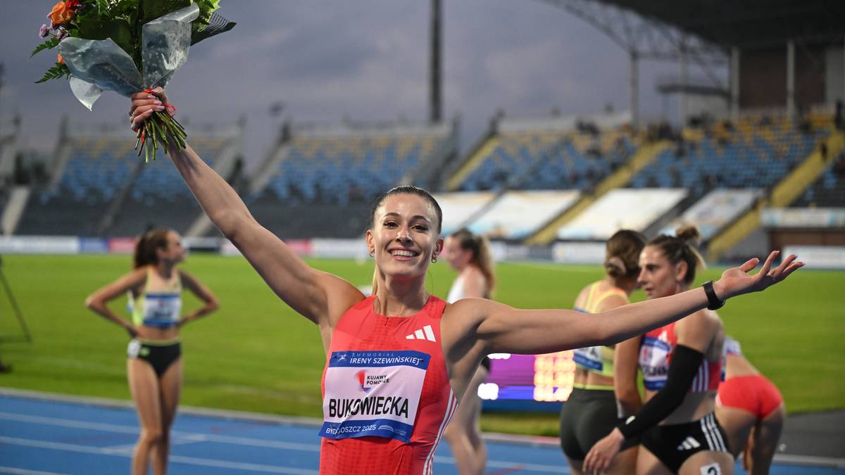 Uśmiechnięta lekkoatletka Ewa Bukowiecka z bukietem kwiatów na ramieniu, podczas ceremonii medalowej na stadionie.