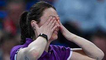 Siatkarka zakrywająca twarz dłońmi w geście rozpaczy.