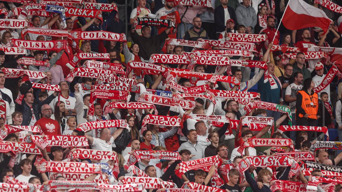 Widzowie na stadionie podczas meczu, trzymający biało-czerwone szaliki z napisem "POLSKA".