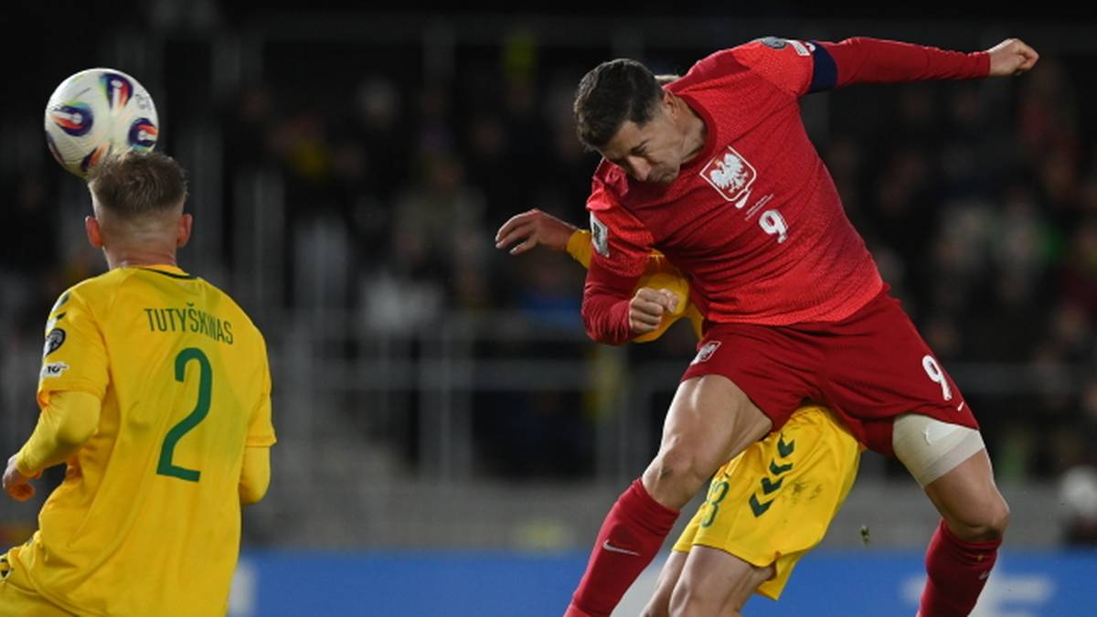 Piłkarz Robert Lewandowski w czerwonej koszulce reprezentacji Polski walczy o piłkę z przeciwnikiem w żółtej koszulce.