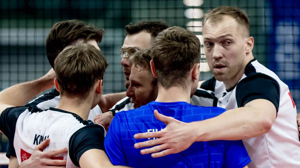 Drużyna siatkarzy w białych i niebieskich strojach stoi w k&oacute;łku, obejmując się nawzajem.