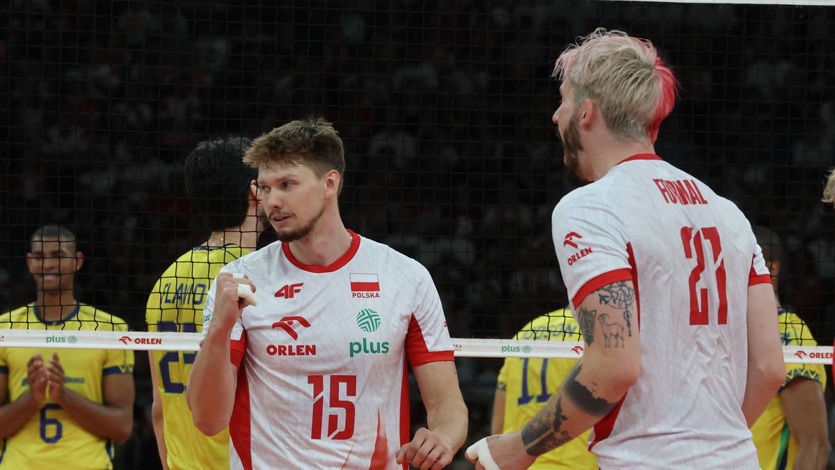 Dwóch polskich siatkarzy w białych koszulkach z czerwonymi elementami podczas meczu.