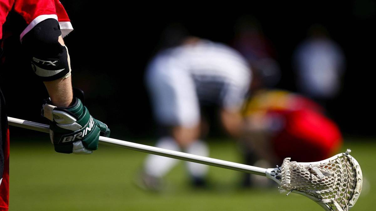 Gracz w rękawicy lacrosse trzyma kij do lacrosse, gotowy do gry na boisku.