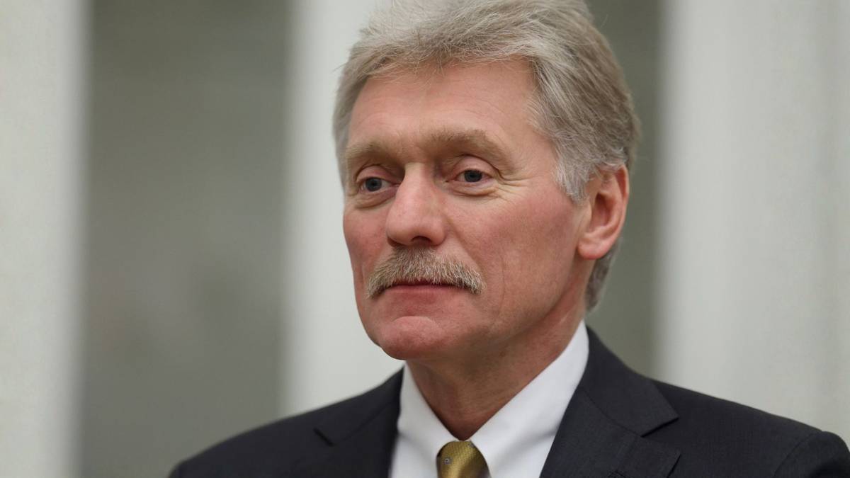 Portret mężczyzny w średnim wieku, z siwiejącymi włosami i wąsami. Ubrany jest w ciemny garnitur i białą koszulę ze złotym krawatem.