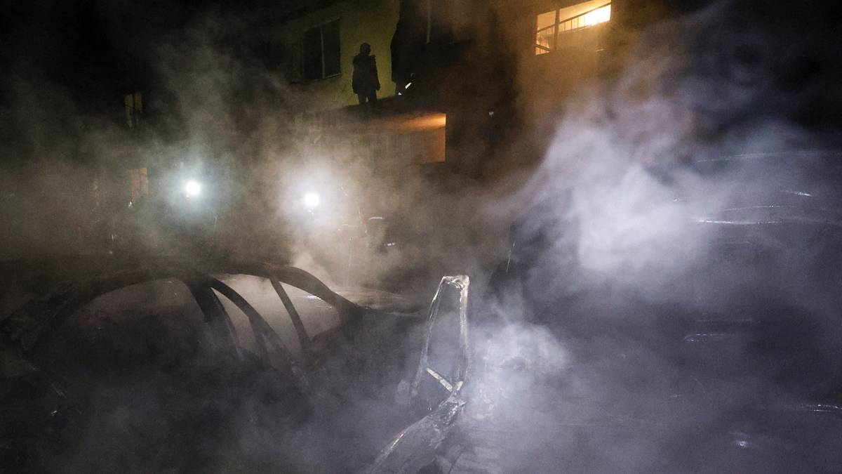 Nocny widok miejsca po ataku dronów w Charkowie, z unoszącym się dymem i światłami pojazdów.