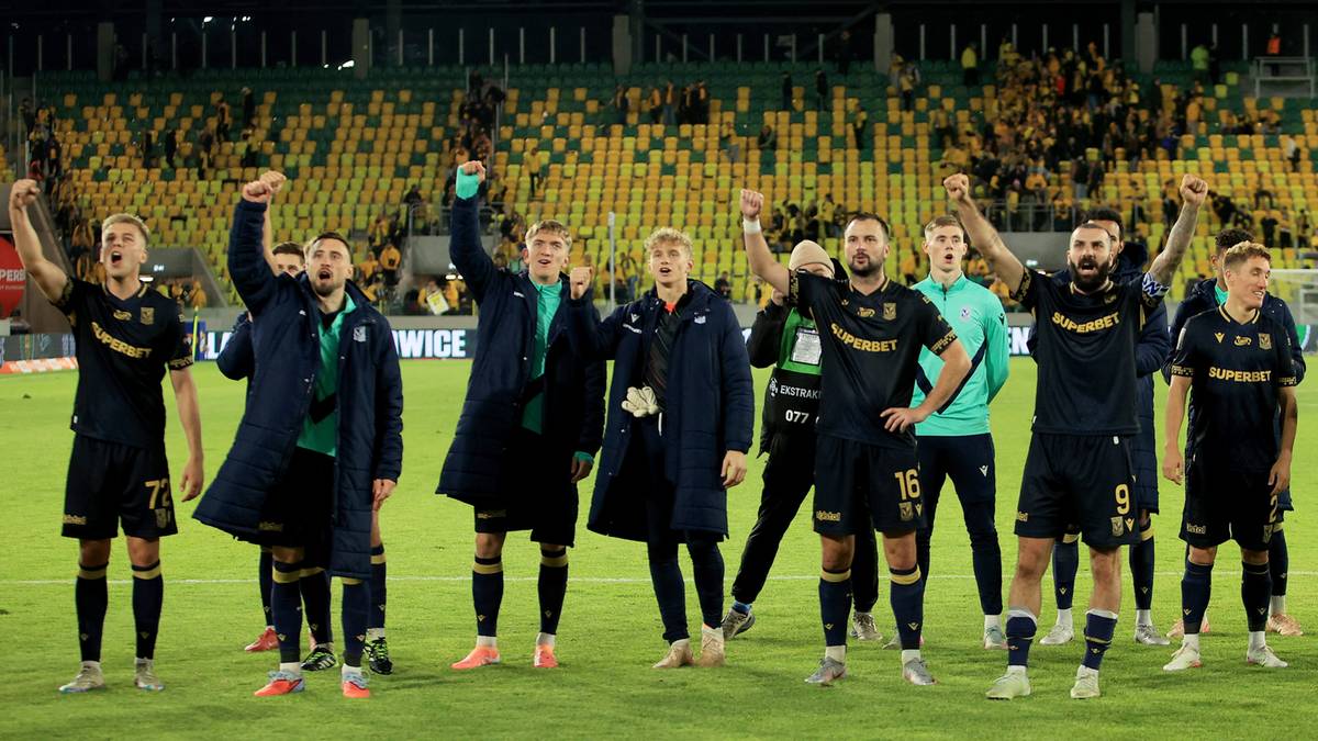 Drużyna piłkarska w niebieskich strojach z niebieskimi płaszczami celebrue zwycięstwo na boisku.