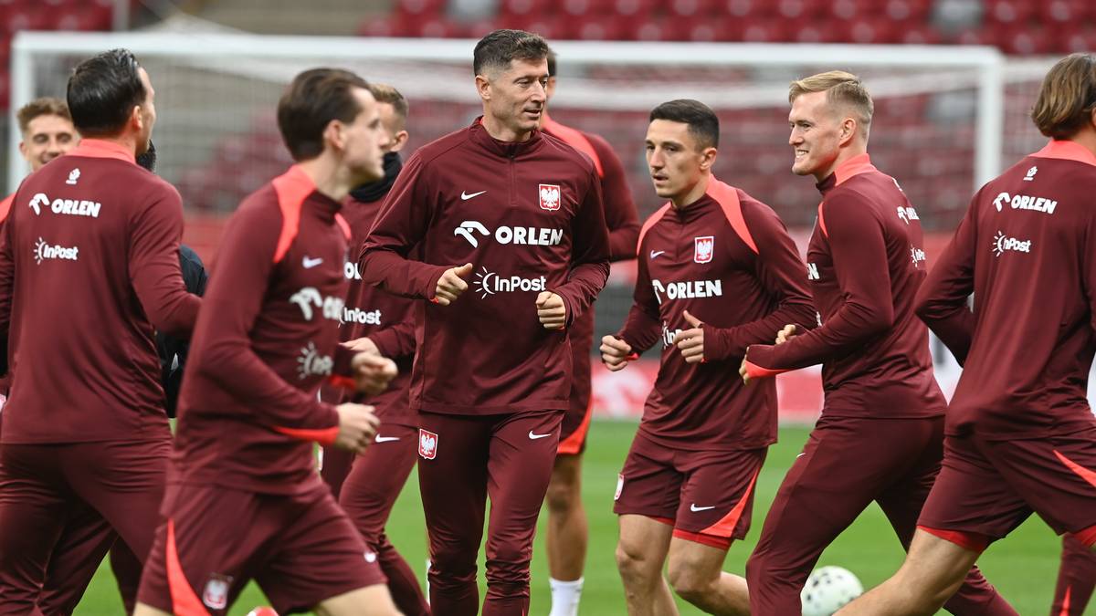 Piłkarze reprezentacji Polski w strojach treningowych na boisku piłkarskim, z Robertem Lewandowskim w centrum.