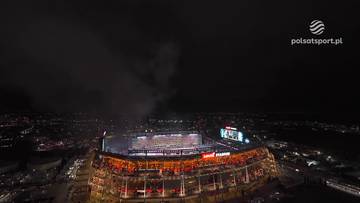 Widok z g&oacute;ry na nocny stadion podczas ceremonii po Super Bowl 2026. Na środku boiska widać sztuczne ognie, a otaczające stadion trybuny są oświetlone.