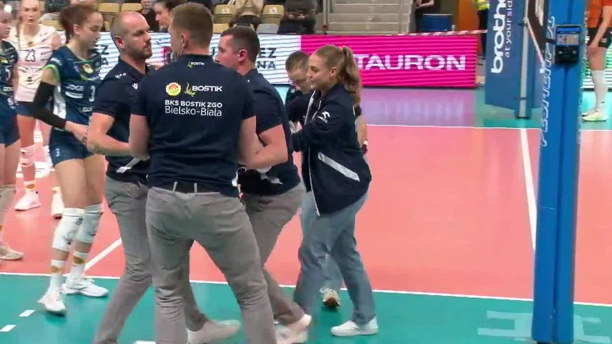 Siłaczka w niebieskim stroju sportowym, z pomocą zespołu medycznego, opuszcza boisko do siatk&oacute;wki po kontuzji.