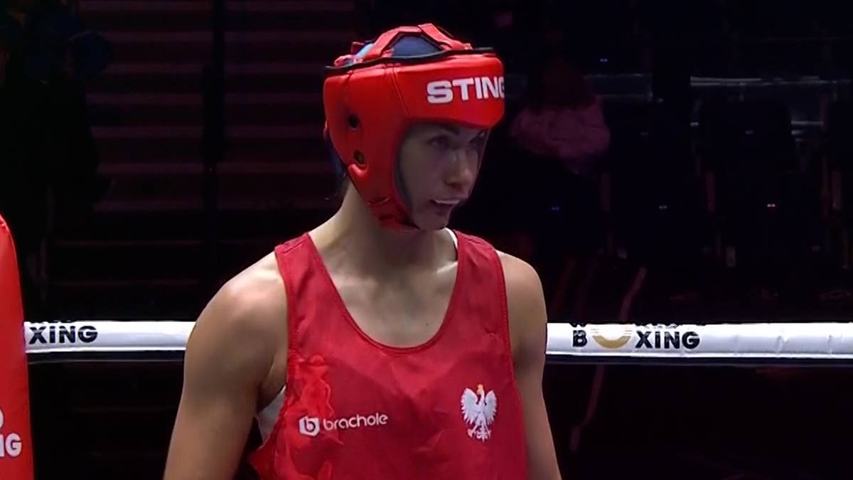 Bokserka Aneta Rygielska w czerwonym kasku i stroju, z zamyśloną miną, stoi w ringu.