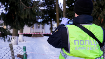 Policjant w kamizelce odblaskowej wykonuje zdjęcie telefonem kom&oacute;rkowym na miejscu zdarzenia.