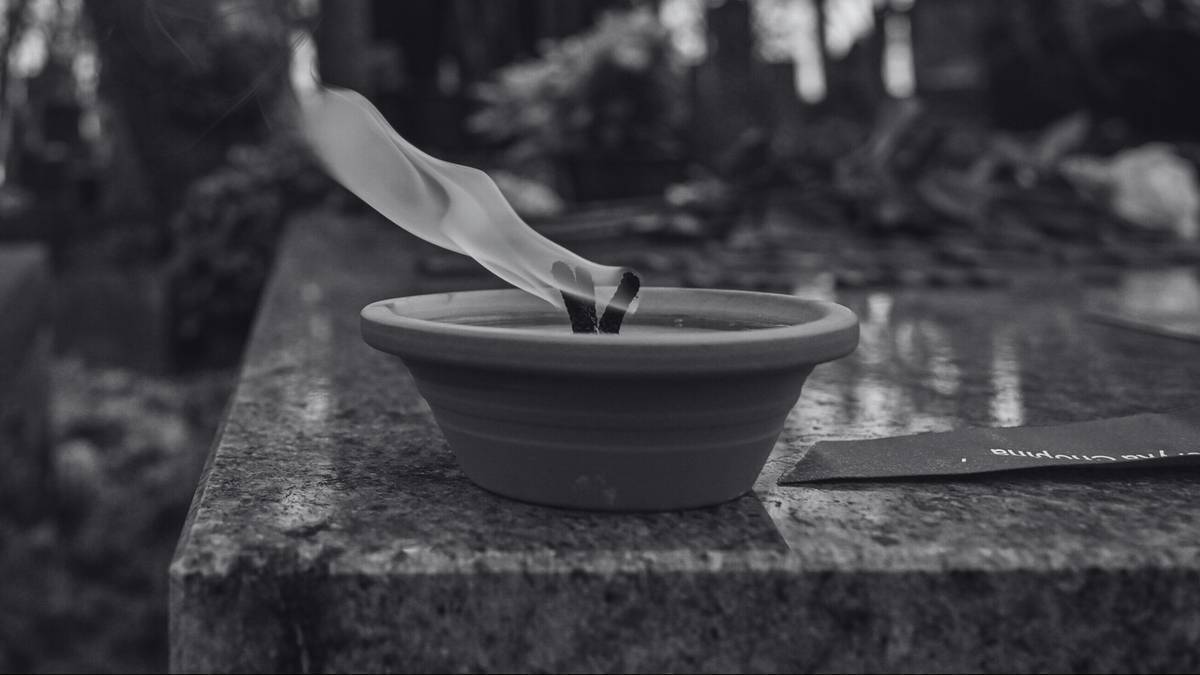 Płonący znicz na kamiennym postumencie.