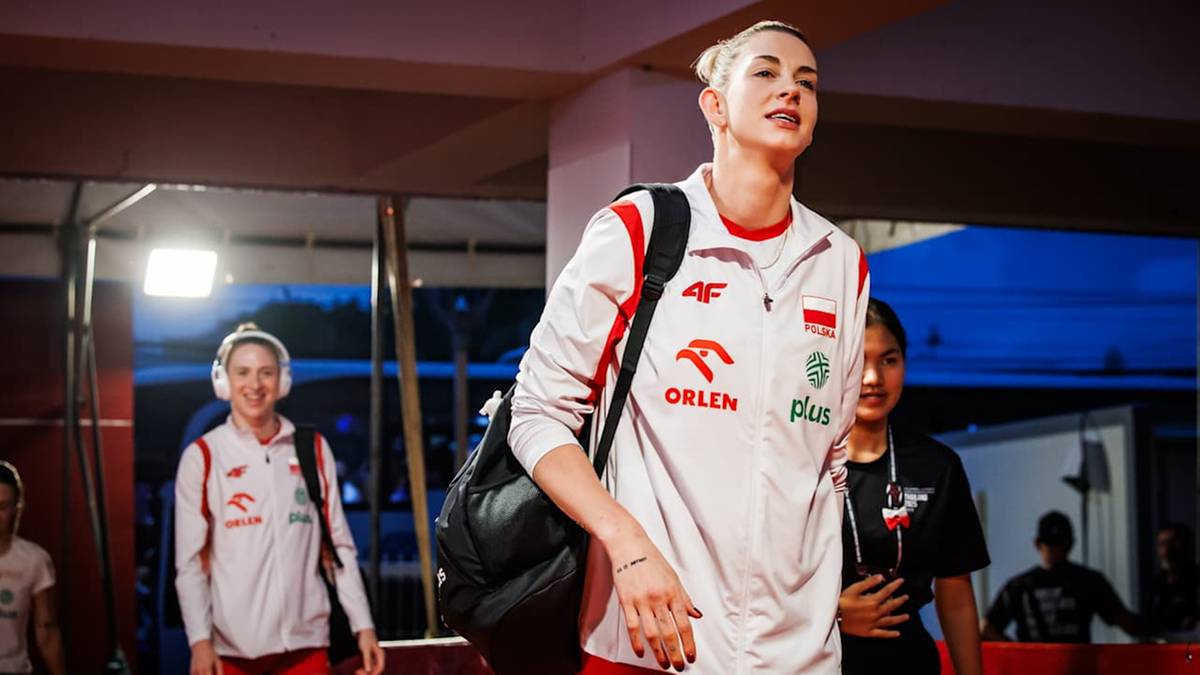 Magdalena Stysiak, siatkarka w białej koszulce reprezentacji Polski z czerwonymi elementami i logo PKOl, idzie przed innymi zawodniczkami.
