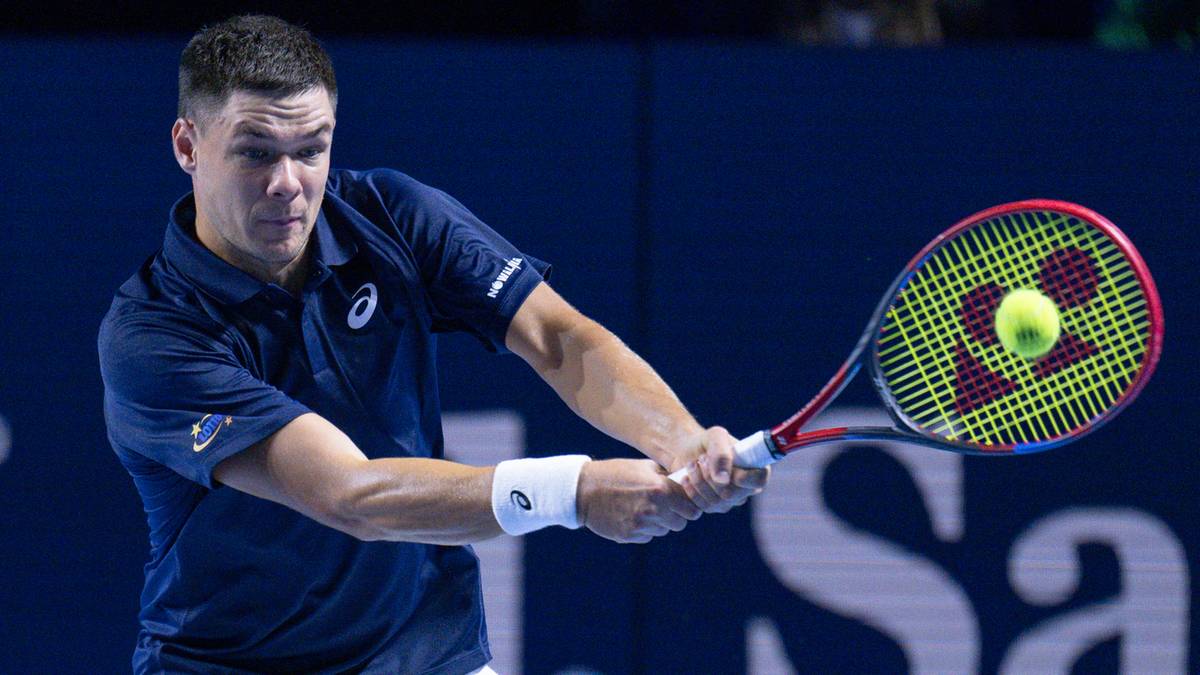 Mężczyzna grający w tenisa, uderzający piłkę rakietą.