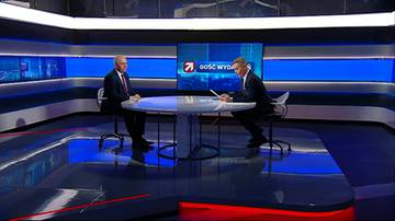 Dw&oacute;ch mężczyzn siedzących przy okrągłym stole w studio telewizyjnym podczas wywiadu. Na ekranie za nimi widnieje logo "Gość Wydarzeń".