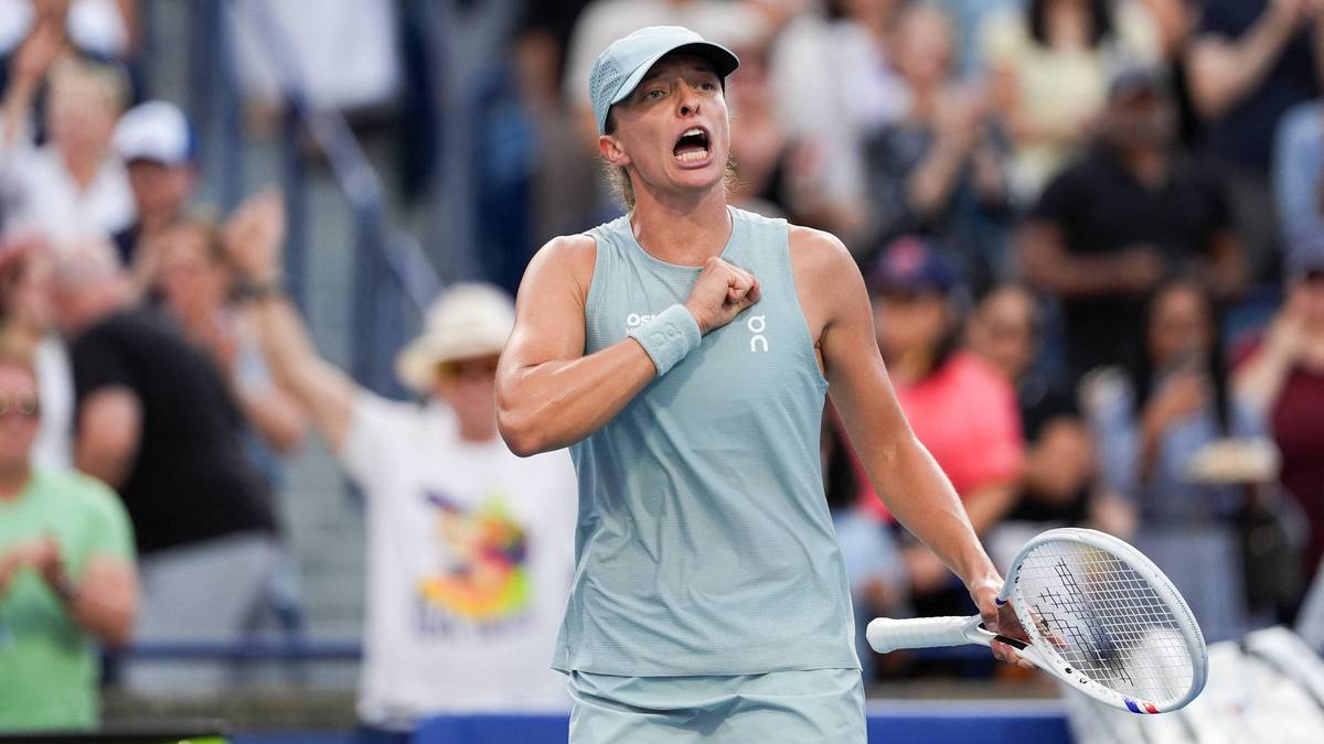 Tenisistka w niebieskim stroju sportowym z czapką na głowie, krzyczy z radości, trzymając rakietę tenisową w prawej ręce. W tle widać publiczność na trybunach.