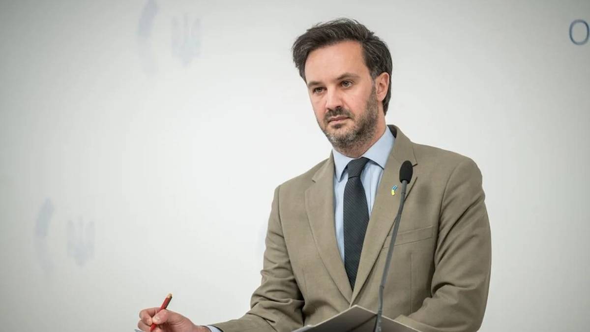 Mężczyzna w garniturze przemawia przy m&oacute;wnicy.