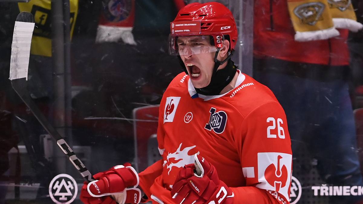 Hokeista w czerwonym stroju z otwartymi ustami, patrzący przed siebie.