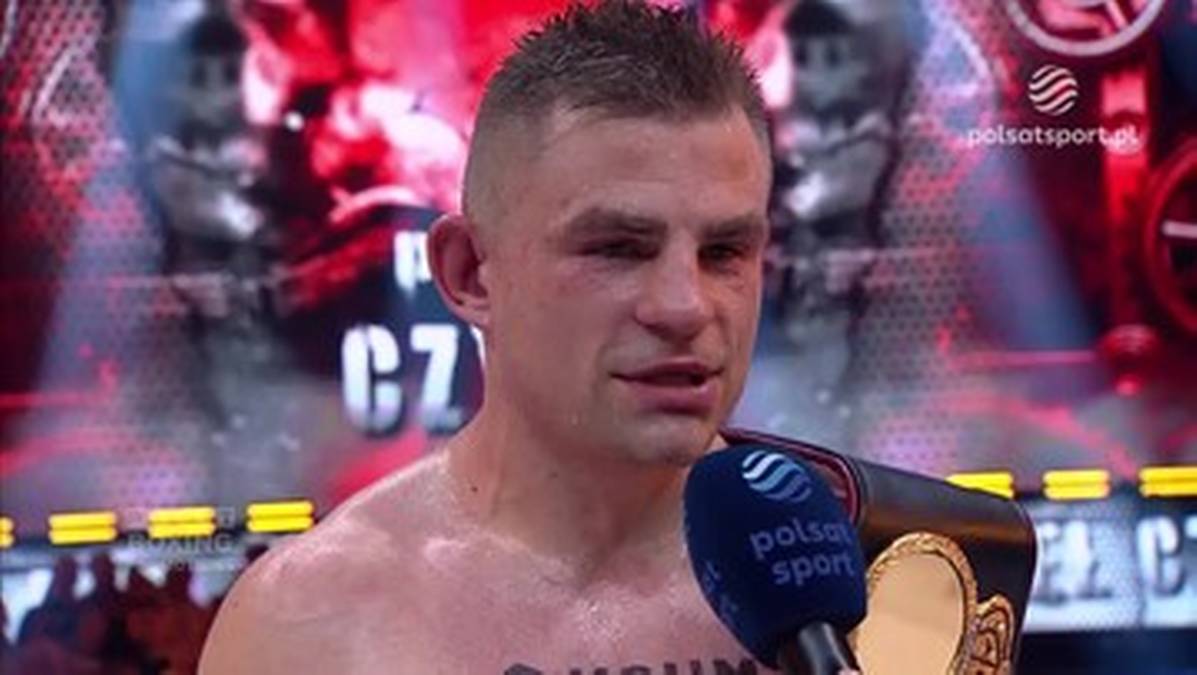 Portret boksera Krzysztofa Czyżyka z mikrofonem Polsat Sport przed twarzą.