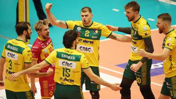 Siatkarze w żółto-zielonych strojach świętujący na boisku.