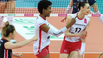 Siatkarka w białym stroju z numerem 17 radośnie komunikuje się z koleżanką z drużyny podczas meczu siatk&oacute;wki.