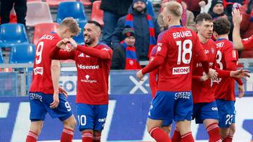 Piłkarze w czerwonych strojach świętują na boisku piłkarskim.