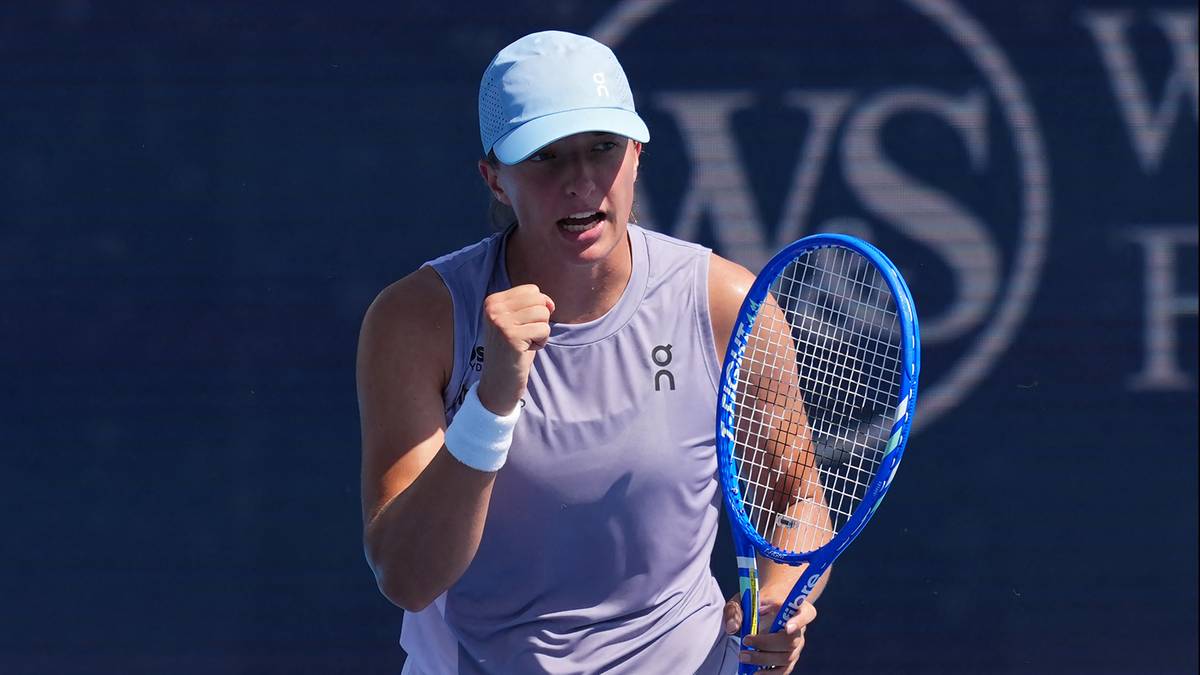 Iga Świątek, polska tenisistka, w akcji podczas meczu, z rakietą w ręku i uniesioną pięścią, wyrażając radość lub determinację.