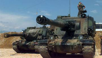 Dwa francuskie wozy bojowe stojące na pustynnym terenie, jeden z widocznym żołnierzem na dachu.