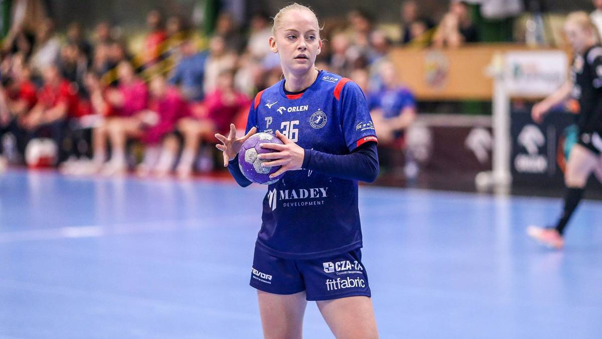 Zawodniczka piłki ręcznej Lucyna Sobecka w niebieskim stroju trzyma piłkę i patrzy przed siebie.