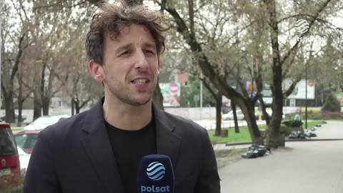 Filip Gawęcki, mężczyzna m&oacute;wiący do mikrofonu Polsat Sport, w tle drzewa.