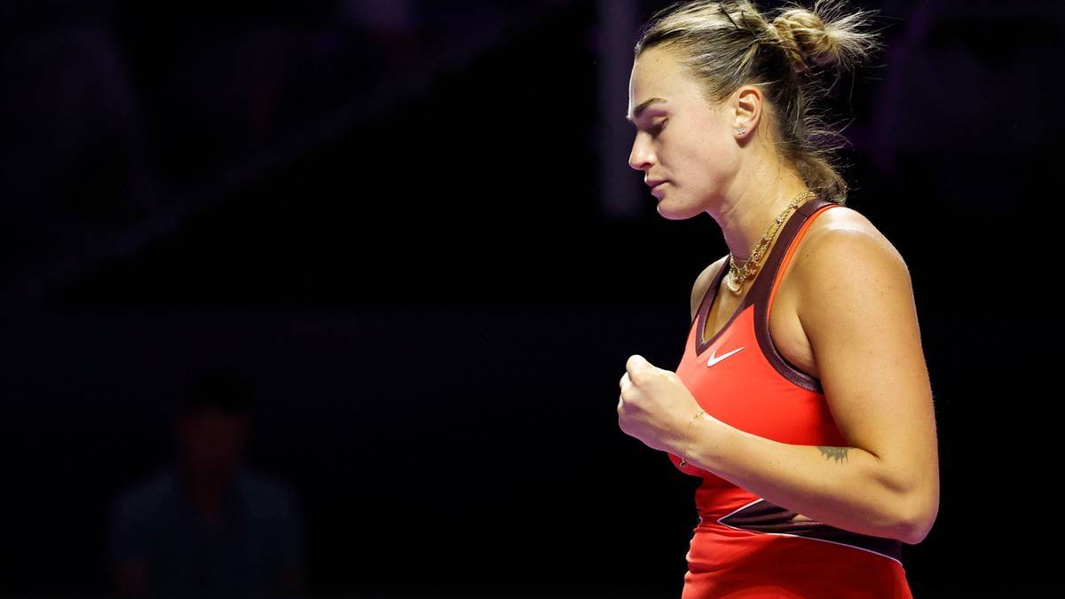 Aryna Sabalenka, tenisistka, zaciśniętą pięścią i zamkniętymi oczami, w czerwonym stroju sportowym.