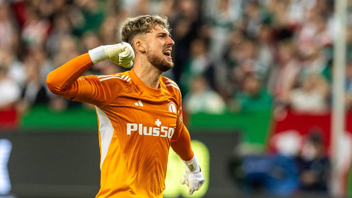 Bramkarz Kacper Tobiasz w pomarańczowej koszulce z logo Plus500, z uniesioną prawą ręką przy skroni, wykrzykujący z radości po awansie do Ligi Konferencji Europy.