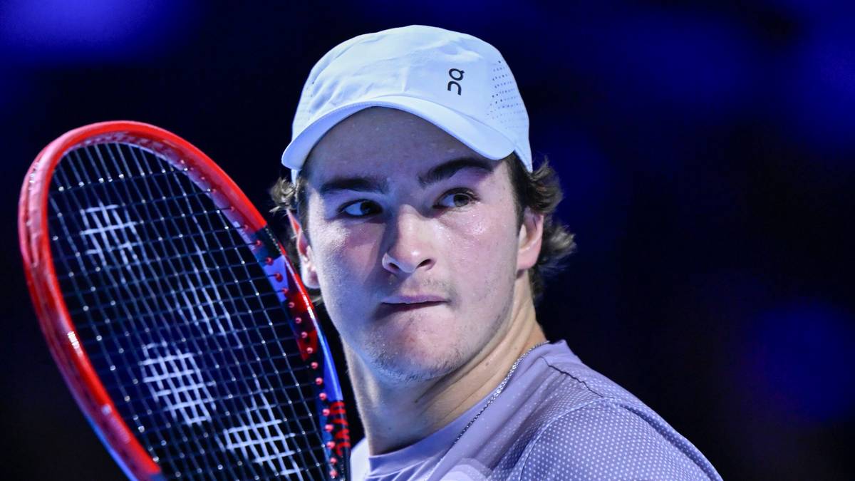 Młody tenisista w białej czapeczce z daszkiem trzyma rakietę tenisową.