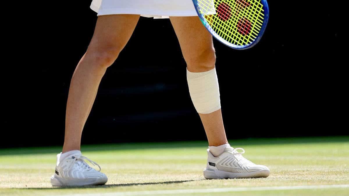 Fragment sylwetki tenisistki z rakietą na trawiastym korcie podczas Wimbledonu.