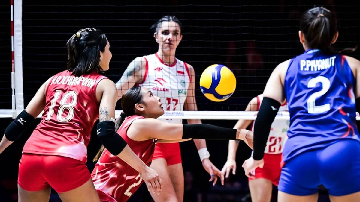 Drużyna siatkarek rywalizuje podczas meczu, widoczne zawodniczki w czerwonych i niebieskich strojach, piłka w powietrzu.