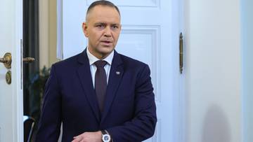 Prezydent Andrzej Duda w garniturze i krawacie, stojący przy drzwiach.