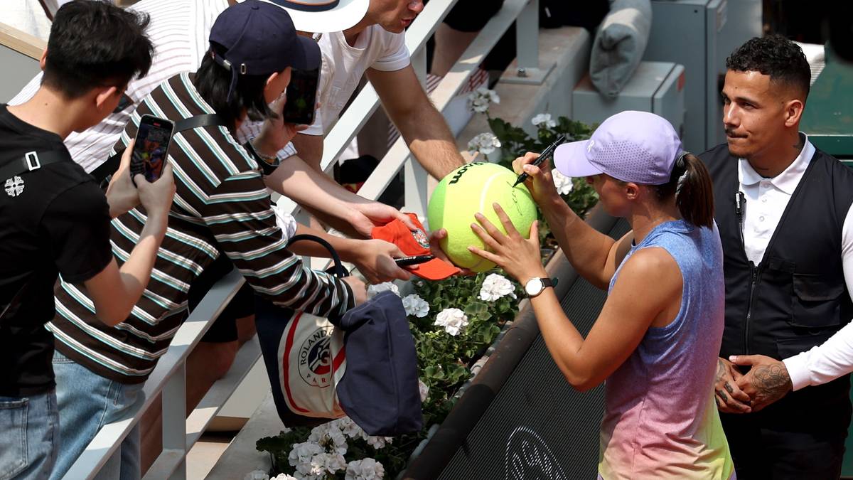 Tenisistka daje autograf fanom na piłce tenisowej.