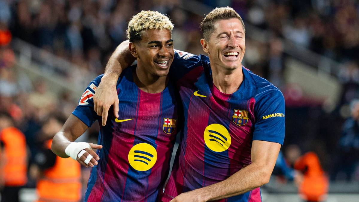 Dwóch piłkarzy FC Barcelony, Robert Lewandowski i Lamine Yamal, cieszą się razem na boisku, obejmując się ramionami.