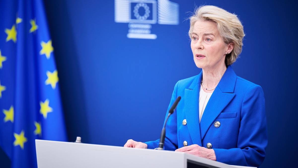 Ursula von der Leyen, przewodnicząca Komisji Europejskiej, przemawia za mównicą na tle flagi Unii Europejskiej.