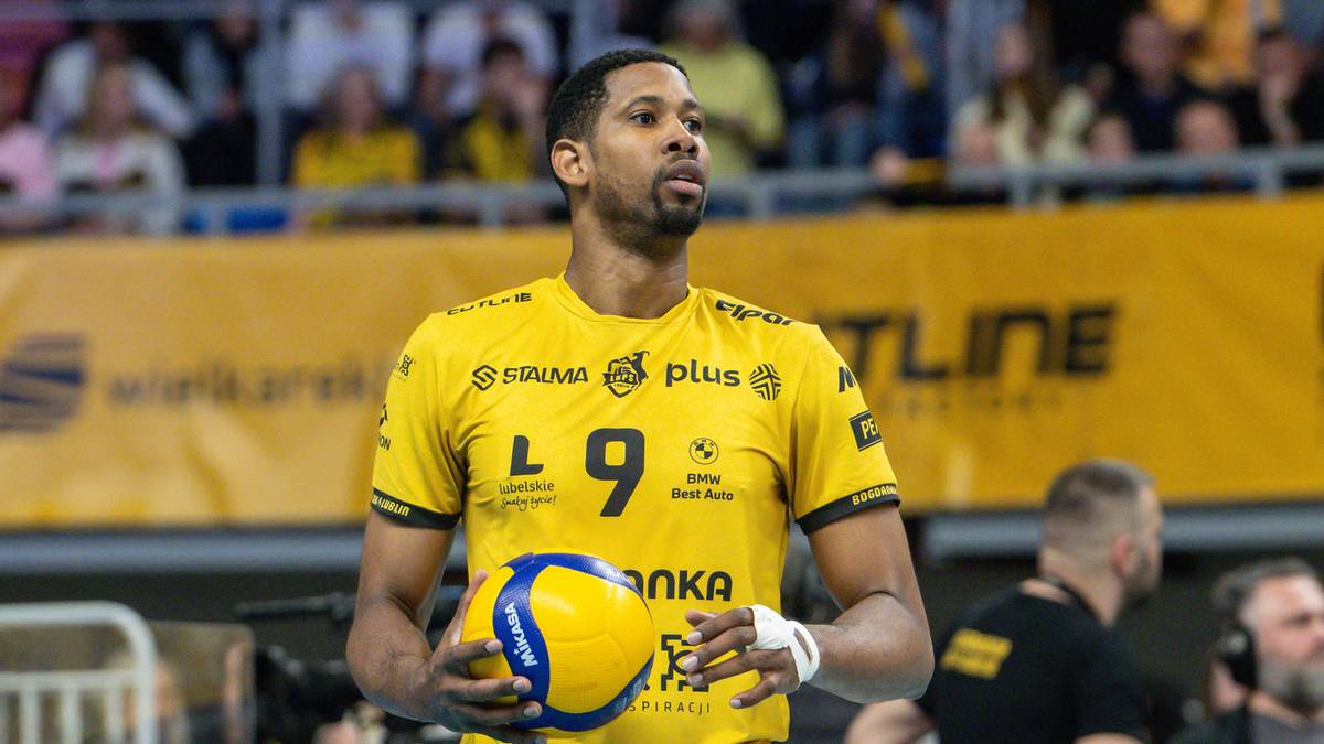 Siatkarz w żółtej koszulce z numerem 9 trzymający piłkę siatkową.