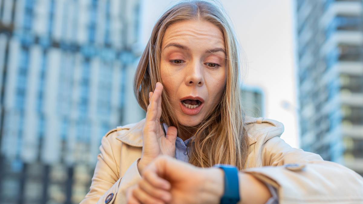 Kobieta spogląda zdziwiona na sw&oacute;j zegarek.