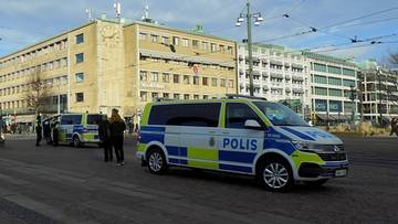 Trzy radiowozy policyjne marki Volkswagen Transporter zaparkowane na ulicy w mieście.