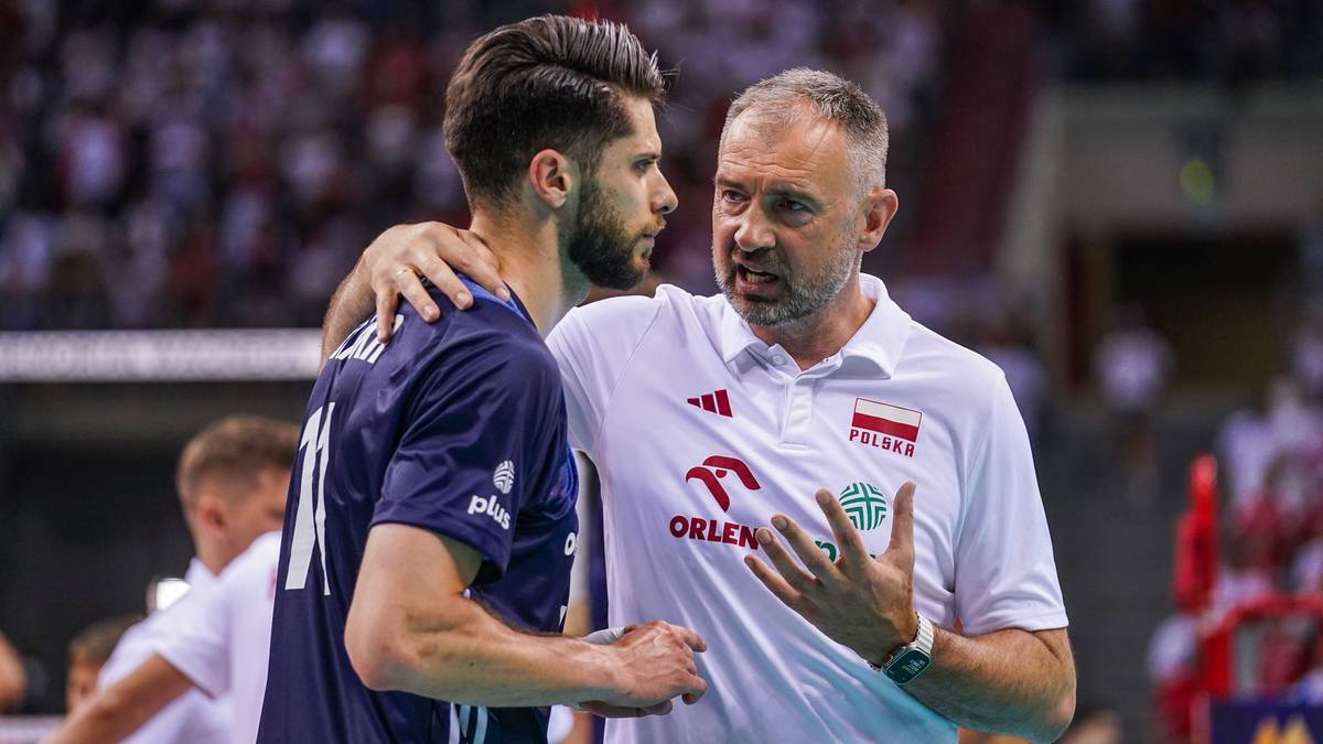 Dw&oacute;ch mężczyzn w strojach sportowych, jeden rozmawia z drugim, gestykulując.