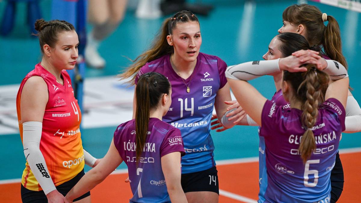 Grupa zawodniczek siatkarskich w barwach klubowych rozmawiających ze sobą na boisku.