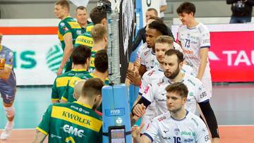 Siatkarze drużyny Warty Zawiercie w białych strojach świętują zwycięstwo, otoczeni przez zawodnik&oacute;w drużyny przeciwnej w zielono-ż&oacute;łtych strojach.