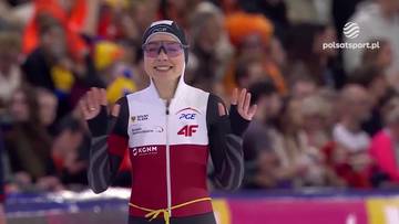 Kaja Ziomek-Nogal w stroju sportowym, uśmiechnięta, z rękami uniesionymi w geście radości lub pozdrowienia, przed publicznością.